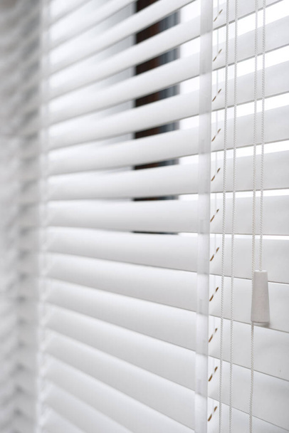 Concept of modern window blinds for sunlight protection in room. Selective focus of wooden jalousie with horizontal slats on plastic window. Advertising of apartment decor with natural material - Photo, Image