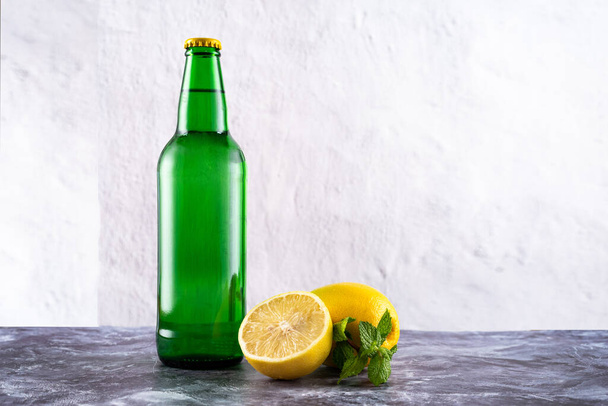 Zielona szklana butelka i cytryny z miętą. Słodka woda gazowana. Lemoniadę. Widok z przodu. - Zdjęcie, obraz