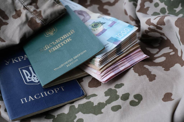 Ukrainian military ID and hryvnia on military uniform. Payments to soldiers of the Ukrainian army, salaries to the military. War in Ukraine - Photo, Image