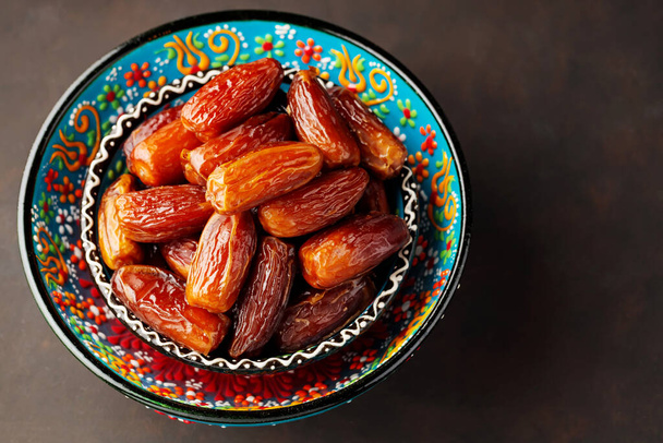 Dried dates in bowl on a dark background. Bowl of pitted dates. Food for Ramadan. Top view. Copy space - Foto, Bild