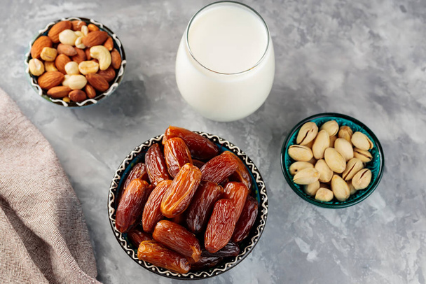 Dried dates, nuts and milk on concrete. Ramadan (Ramazan) food on a gray background. Ramadan kareem fasting month concept. Top view - Zdjęcie, obraz