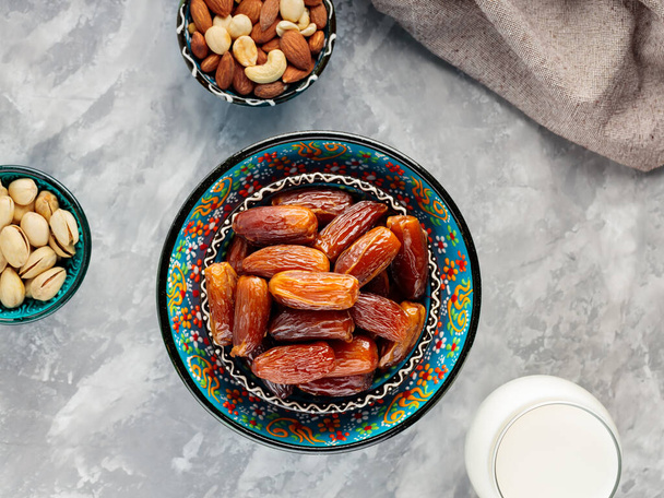 Dried dates, nuts and milk on concrete. Ramadan (Ramazan) food on a gray background. Ramadan kareem fasting month concept. Top view - Фото, зображення