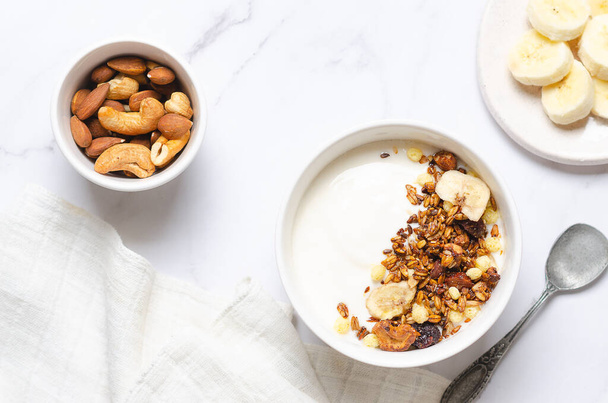 Υγιεινό πρωινό με γιαούρτι, granola και ξηρούς καρπούς σε λευκό φόντο. - Φωτογραφία, εικόνα