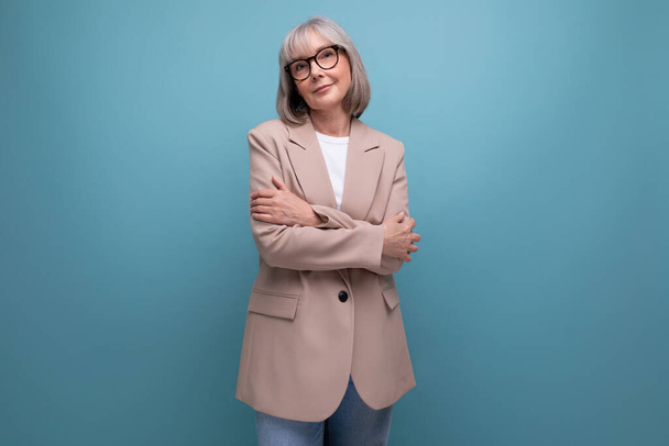 60s zakenvrouw in een jas staat vol vertrouwen op een heldere achtergrond met kopieerruimte. - Foto, afbeelding