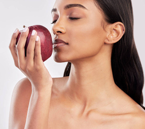 Étkezési, alma vagy egészséges indiai nő bőrápoló szépség vagy wellness stúdióban fehér alapon. Élelmiszer táplálkozás, csukott szemmel vagy arcát lány modell piros gyümölcsök előmozdítása C-vitamin vagy diéta. - Fotó, kép