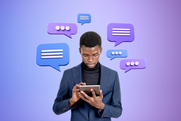 Black serious businessman typing in tablet, text message speech bubbles on gradient background. Concept of social media, business conversation and forum - Foto, Imagen