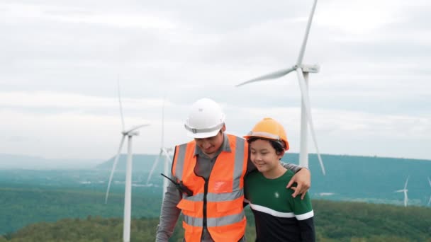 Engenheiro com seu filho em um parque eólico no topo de uma colina ou montanha no campo. Ideal progressivo para a futura produção de energia renovável e sustentável. Produção de energia a partir de turbinas eólicas. - Filmagem, Vídeo