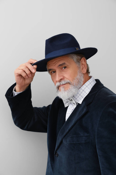 Attractive senior man in stylish hat on light background - Fotoğraf, Görsel