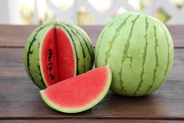 Different delicious ripe watermelons on wooden table - Φωτογραφία, εικόνα