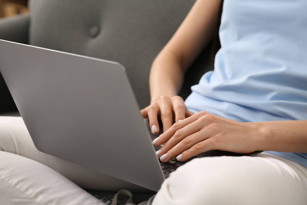 Woman working with laptop on sofa, closeup - Zdjęcie, obraz