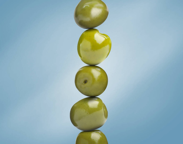 Stack of whole olives on light blue background - Fotoğraf, Görsel