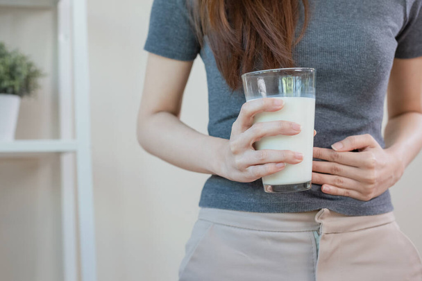 Asian female holding glass milk. resistance deny drinking milk, symptom lactose allergy, concept of health problem, women intolerance ingredient from calcium, stomach ache painful. - Фото, изображение
