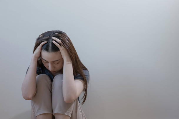 Nainen, jolla on masennus istuu yksin kädet kattavat kasvot makuuhuoneen nurkkaan. Naisen päänsärky onneton tunne. nuorten ahdistuneisuus mielenterveysongelmien epätoivo. - Valokuva, kuva