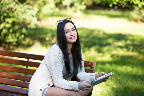 дівчина студент електронний планшет, що сидить на лавці в парку
 - Фото, зображення