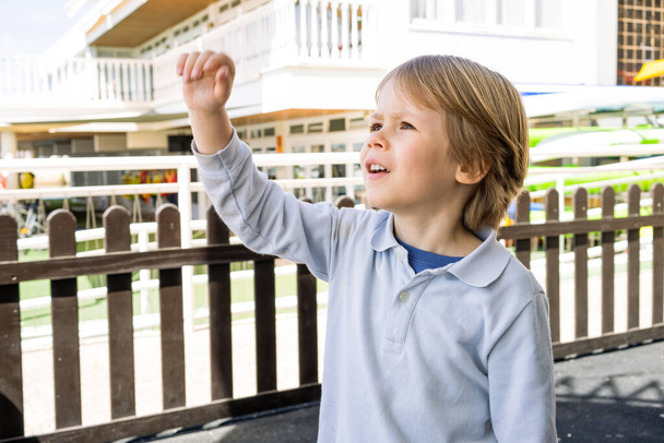 青いTシャツを着た笑顔の金髪の男の子の肖像画が屋外で遊んでいます。幸せな子供やライフスタイル. - 写真・画像