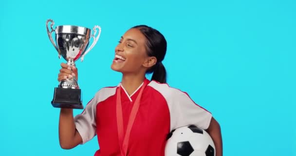 Sports winner, trophy and excited woman with soccer player award, match competition victory or football achievement. Winning, studio celebration portrait and happy female athlete on blue background. - Footage, Video