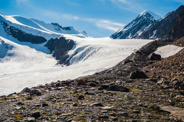 The way to the Aktru glacier. Snowy high-altitude plateau. Alpine landscape with snow-capped mountain peak and sharp rocks under blue sky. Colorful sunny mountain scenery with snow mountain top.  - Photo, Image