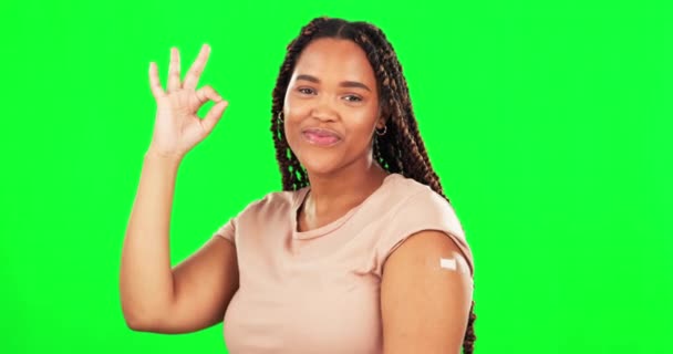 Зеленый экран, вакцина и счастливая женщина с мигалкой, лакомый знак для рук и безопасная для здоровья ковий. Портрет женской модели, бинт и жест ОК в согласии с вакцинацией, иммунитетом и эмодзи. - Кадры, видео