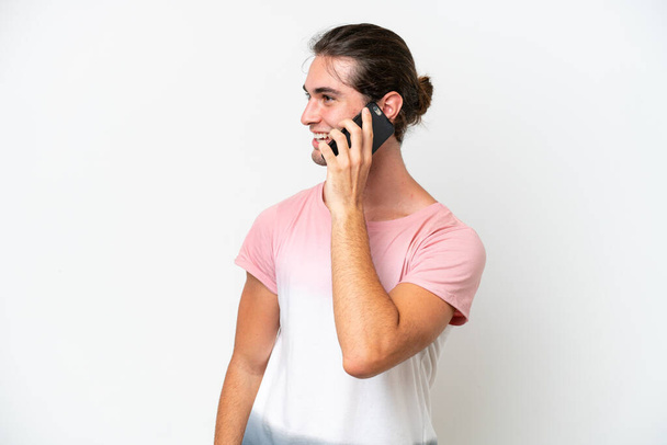 Kaukasischer gutaussehender Mann isoliert auf weißem Hintergrund, der ein Gespräch mit dem Mobiltelefon mit jemandem führt - Foto, Bild