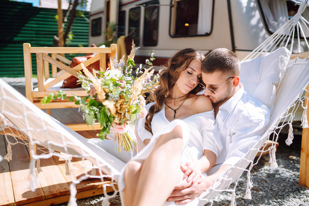 Newly made couple are resting in a trailer. Newlyweds tenderly embrace, enjoy each other in a van, camping in a trailer. Together. Wedding. Romantic moment. - Fotografie, Obrázek