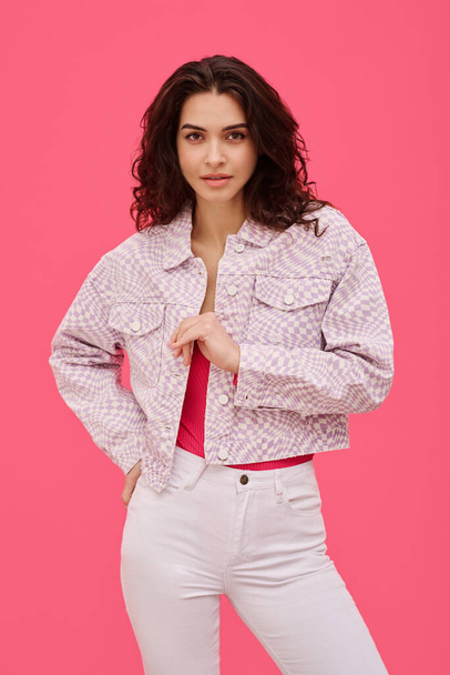 Portrait of beautiful woman with curly hair looking with tempted sight at camera standing against pink background - Photo, Image