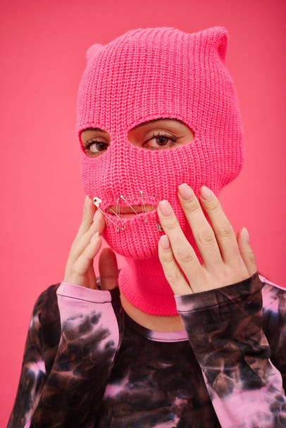 Portrait of young woman in pink balaclava with sewed mouth looking at camera, she fighting for women rights - Photo, image