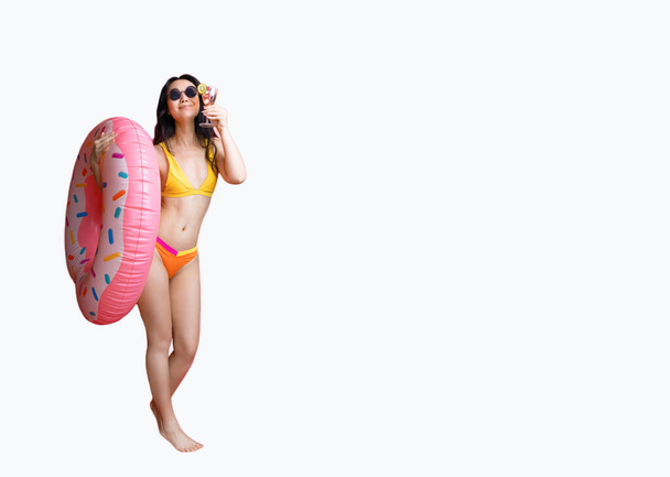 Full body glamour asian woman in swimsuit is drinking fresh juice or cocktail, enjoying rest, vacation resort. Studio shot isolated on white background. Summer mood. - Valokuva, kuva