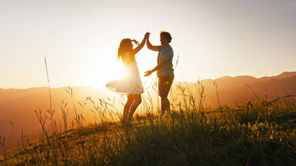 Man and woman dance on the summer meadow with grass at sunrise - Foto, immagini