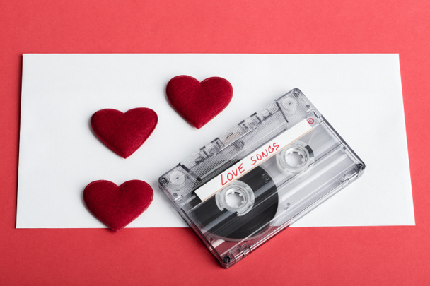 Audio cassette tape op rode achtergrondkleur met stof hart - Foto, afbeelding