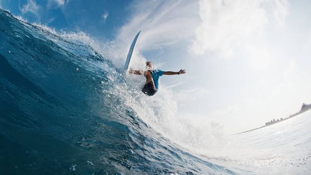 Pro surfer rides the wave. Young man surfs the ocean wave in the Maldives and aggressively turns on the lip. Splitted above and underwater view - Фото, изображение