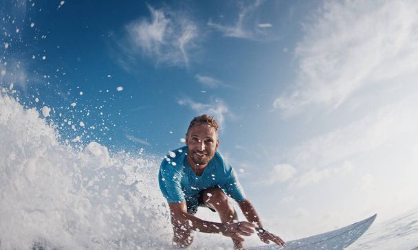 Happy surfer rides and smiles. Young man surfs the ocean wave in the Maldives and smiles - Foto, Bild