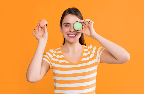 glad girl with macaron on yellow background. - Foto, imagen