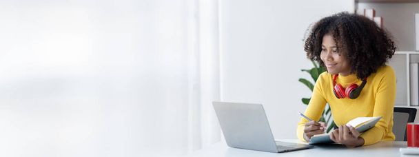 American teenant woman sitting in white room with laptop, είναι φοιτήτρια που σπουδάζει online με laptop στο σπίτι, φοιτήτρια που σπουδάζει online, online web education concept. - Φωτογραφία, εικόνα
