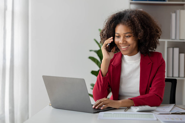 A young American woman is a start-up businesswoman, she sits in her office and talks on the phone with her partner, management and business from a new generation. Startup business management concept. - Photo, Image