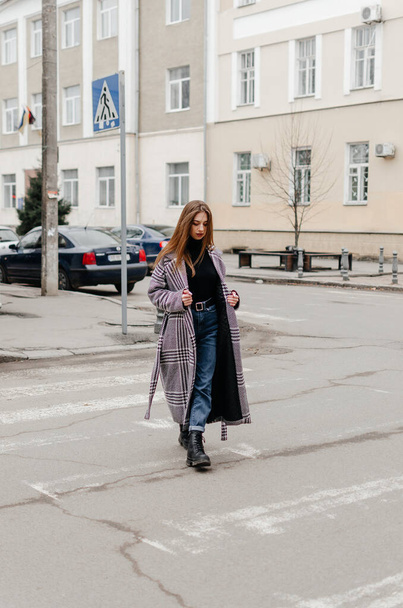a girl in a coat crosses the road - Фото, зображення
