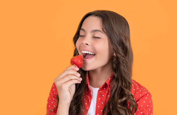 happy teen girl eat strawberry on yellow background. - Φωτογραφία, εικόνα