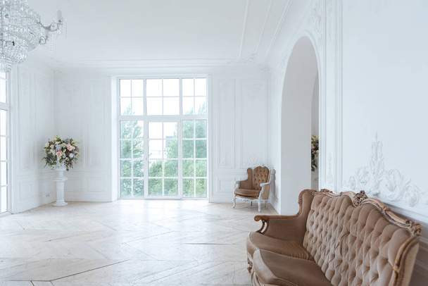chic white huge spacious hall with a minimum of expensive antique furniture. Baroque interior design with ornament on the walls and parquet on the floor. - Fotó, kép