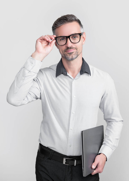 mature man in eyeglasses holding pc on grey background. - Foto, immagini