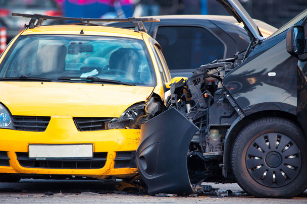 Tässä kuvassa kuvataan sinisen ja keltaisen ajoneuvon välisen auto-onnettomuuden jälkiseuraukset. Roskat roskaavat tietä, kun pelastushenkilöstö osallistuu tapahtumapaikalle - Valokuva, kuva