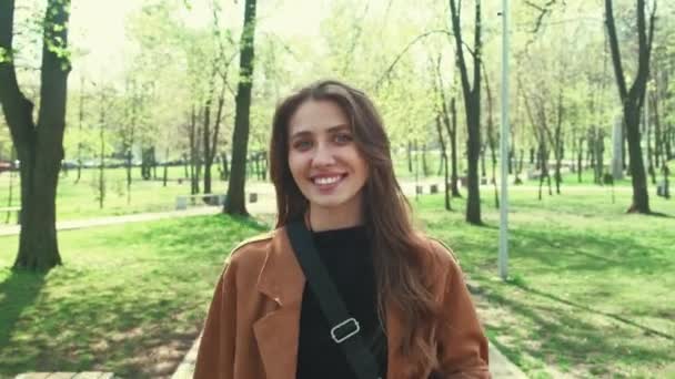 Motion video van jonge charmante vrouw wandelen in het stadspark tijdens de lente. - Video