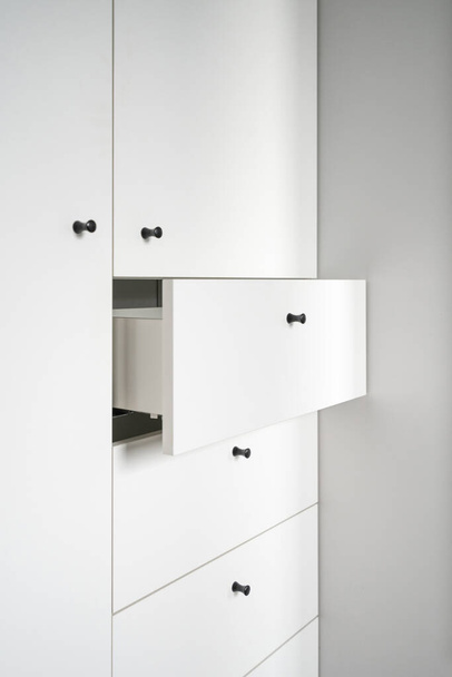 open drawer in wooden white closet in apartment, storage of bed linen and fresh towels inside, detail of modern clothes cabinet in furniture store - 写真・画像