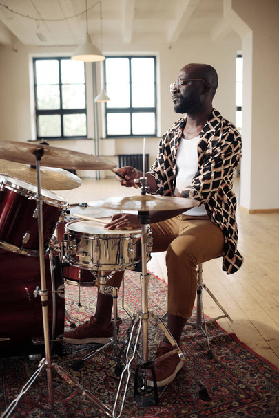 アフリカの若い男で眼鏡のドラムセットに座って、スタジオでドラムを演奏することを学ぶ - 写真・画像