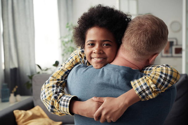 Portrait of African happy adoptive boy hugging his foster dad and smiling at camera - Zdjęcie, obraz