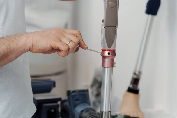 Mechanizm mocowania nowej sztucznej kończyny za pomocą śrubokrętu podczas montażu protezy nogi w warsztacie - Zdjęcie, obraz