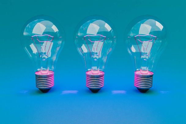 three retro style lightbulbs with glowing filament standing in a row on infinite colorful background; creativity design concept; 3D Illustration - Foto, Imagem