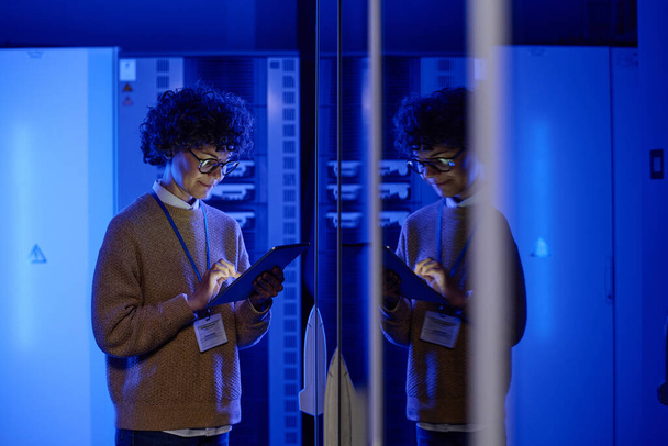 L'amministratore IT femminile cammina nel corridoio del server diagnosticando le prestazioni del sistema hardware nel data center - Foto, immagini