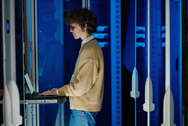 Técnico feminino usando laptop ao analisar servidor em data center grande - Foto, Imagem