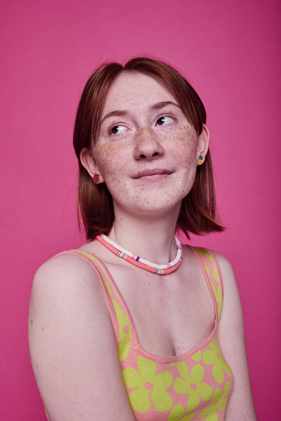 Porträt eines Teenagers mit roten Haaren, der romantisch vor rosa Hintergrund posiert - Foto, Bild
