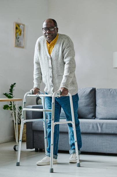 Portrét afrického zralého muže se snaží chodit s chodcem během jeho rehabilitace doma - Fotografie, Obrázek