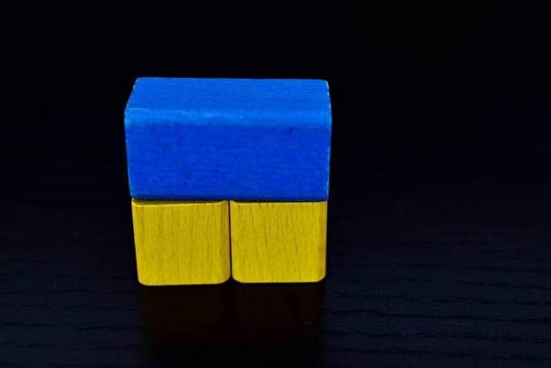 деревянные голубые и желтые геометрические фигурки на черном столе - Фото, изображение
